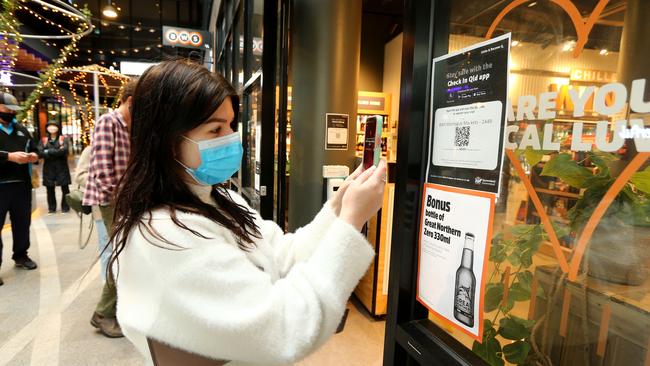 A woman uses the state government's QR phone code for contract tracing as required before entering a shop in West End, Brisbane, on Saturday. Picture: David Clark