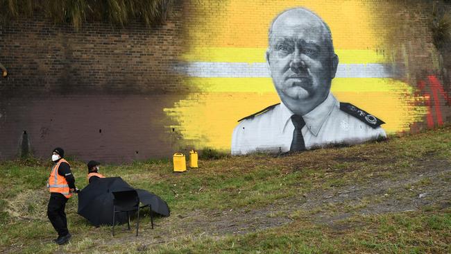 Security guards watch over a new mural of RFS hero Shane Fitzsimmons at Erskineville train station in Sydney on Wednesday. Picture: NCA NewsWire / Joel Carrett