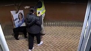 A still from CCTV footage showing a woman, walking her dog, speaking with a man placing a poster for independent candidate Sophie Scamps outside the electorate of sitting Liberal MP Jason Falinski early on Wednesday. Picture: Supplied