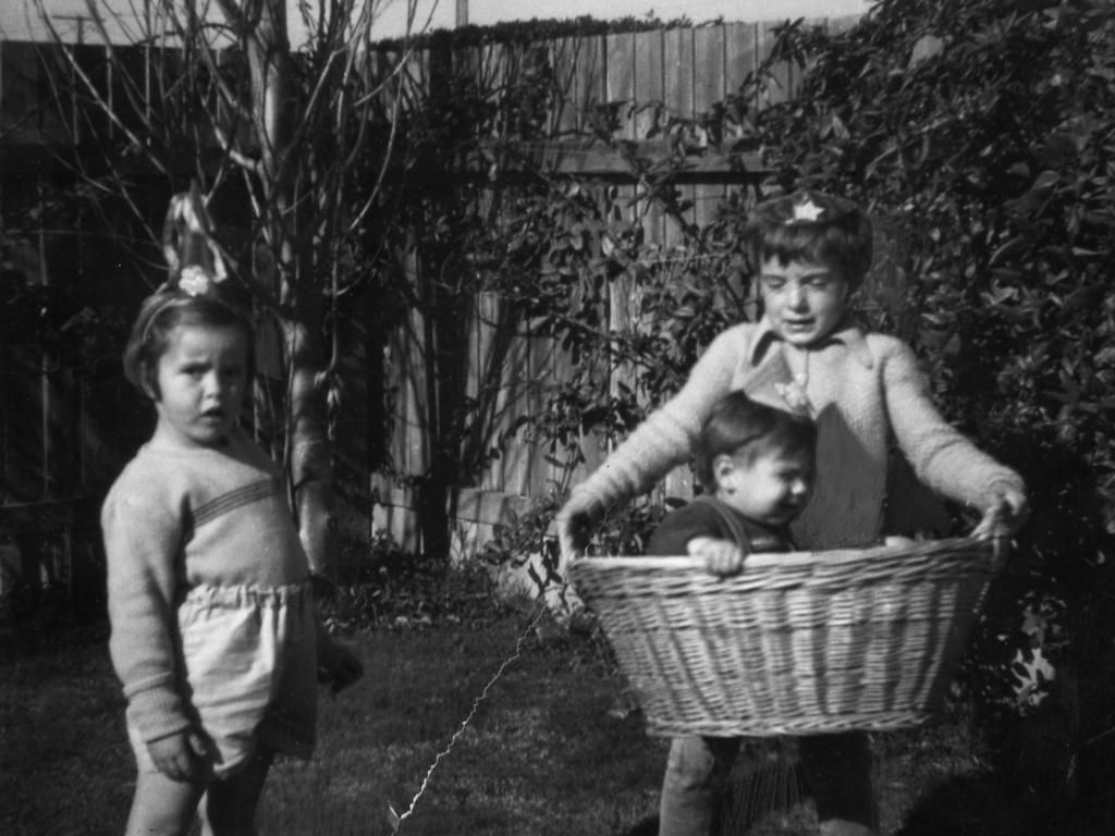 <p>Arnna looks on as Jane gives her baby brother Grant a ride in a washing basket.</p>