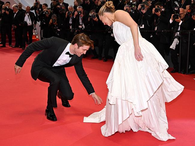 Pattinson helps Lawrence fan her dress train on the red carpet. Picture: Lionel Hahn/Getty Images