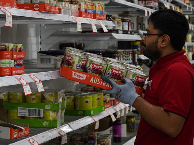 A Coles worker restocking canned goods. Picture: Coles