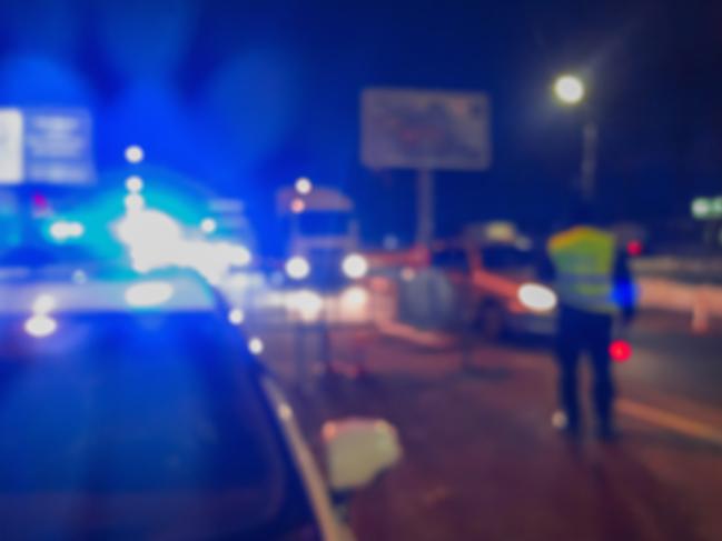 Unrecognizable blurry police car lights and police force officer on night road background, crime scene, night patrolling the city. Abstract blurry image.