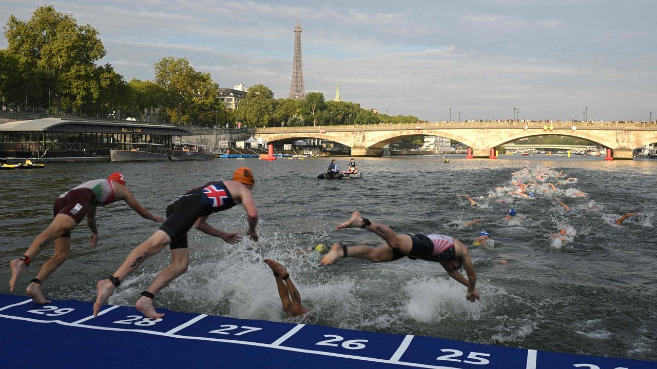 (FILES) Triathlon athletes dive into The Seine river with the Eiffel Tower in the background during the men's 2023 World Triathlon Olympic Games Test Event in Paris, on August 18, 2023. The organisers of the Paris Olympic and Paralympic Games (26 July – 8 September) are in a cold sweat over this commitment: the success of the swimming events in the Seine depends on the quality of its water, which, although it has improved, will still not be satisfactory in the summer of 2023. (Photo by Bertrand GUAY / AFP)