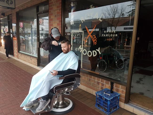 Ben Collins from Blackwood sits outside for his haircut at The Royal Moody after the lights went out across the state. Picture: John Hirst