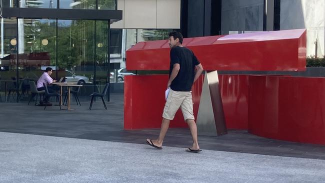 Ryan Dean Harder attempts to hide from journalists by hiding behind a sculpture at the ACT Law Courts. Picture: Julia Kanapathippillai