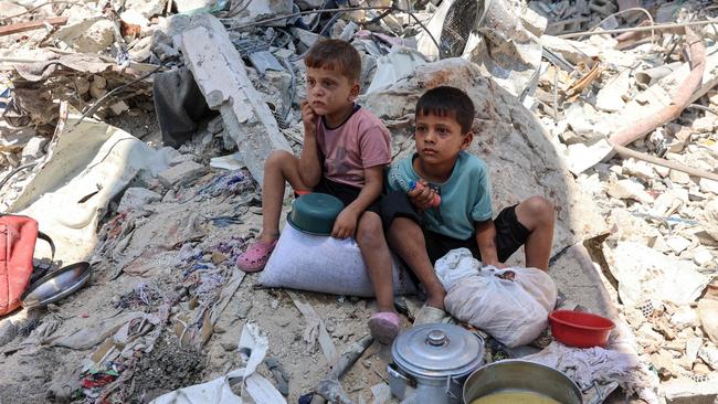 Young Palestinian boys sit amid the rubble of a building with their pots of soup at a food distribution. Picture: AFP