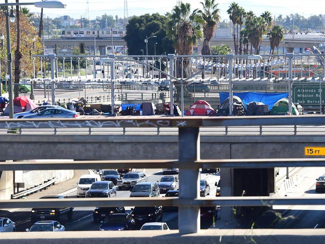 Tents occupied by the homeless line a freeway overpass.