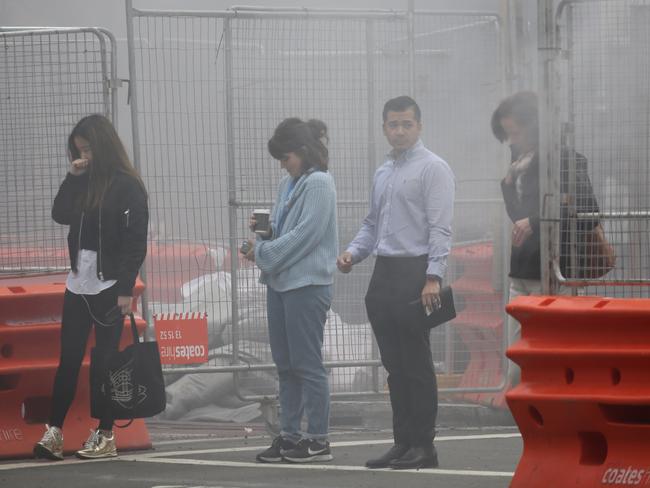 Pedestrians were forced to walk through the smoke. Picture: John Grainger