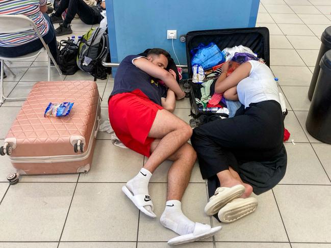 Tourists rest as they wait in the airport's departure hall as evacuations are underway due to wildfires, on the Greek island of Rhodes. Picture: AFP