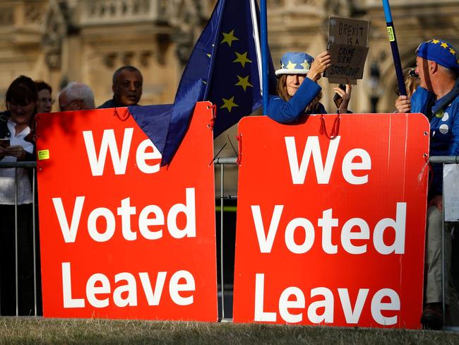 Pro-Brexit and anti-Brexit campaigners with banners and EU flags are seen outside the Houses of Parliament in London. Picture: AFP