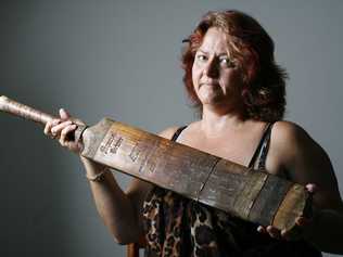 Sharon Wilson sits with a cricket bat found in the cubby house of a Burgess Street property in Raceview where she used to reside. Sharon is keen to find out the story behind the wartime cricket bat. . Picture: Claudia Baxter