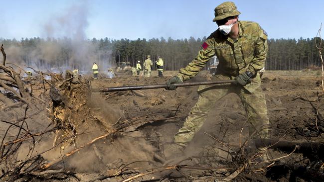 Australian Army Gunner Malachy Brandwood rakes burning wood to assist the Country Fire Service in putting out hot spots in the late stages of the fire. Picture: ADF