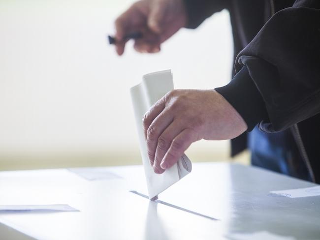 Hand of a person casting a ballot at a polling station during voting. election voting vote polling poll generic Townsville