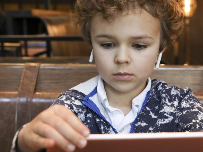 Grayson Hurd, six-years-old, uses AirPods to watch shows on an iPad while his mother Lisa Roberts Hurd does work at a restaurant at the Hyatt Union Square Hotel in New York, New York on January 24, 2020.  Published Credit: Bess Adler for The Wall Street Journal