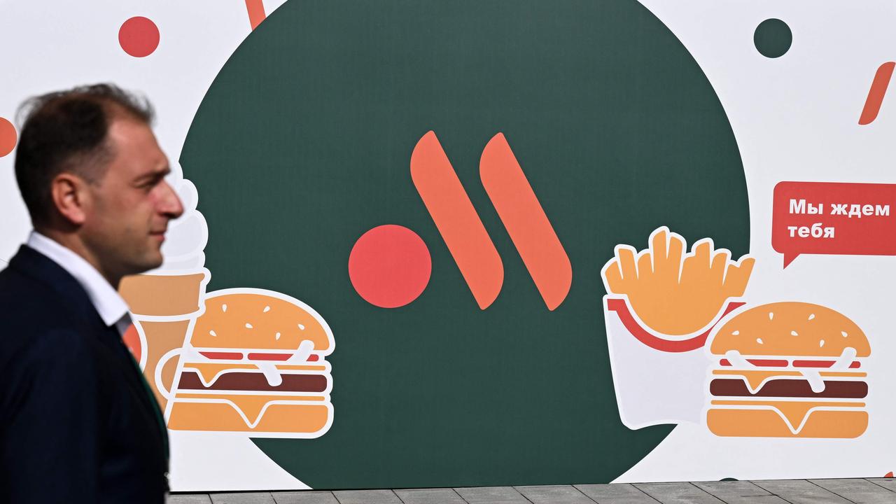 An employee stands in front of the new logo of the Russian version of a former McDonald's restaurant. Picture: Kirill Kudryavtsev / AFP