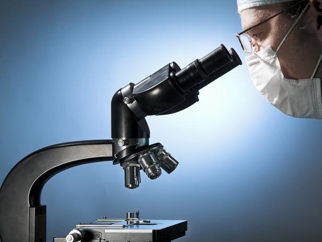 Closeup of a male researcher looking through microscope