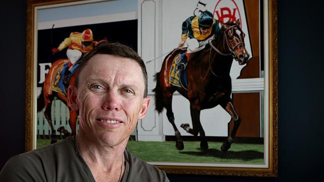 Chris Munce in his study at his Hendra home with a painting of painting of Melbourne Cup-winning mare Jezabeel (right). Picture: