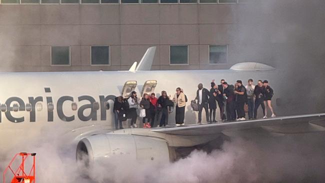 This image courtesy of Branden Williams shows passengers standing on the wing of an American Airlines plane as they are evacuated after it caught fire while at a gate at Denver International Airport in Denver, Colorado, March 13, 2025. (Photo by Branden Williams / Courtesy of Branden Williams / AFP) / RESTRICTED TO EDITORIAL USE - MANDATORY CREDIT 