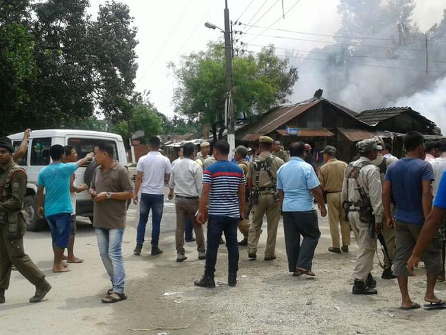 Smoke billows as Indian security personnel and bystanders gather near the site of a militant attack in the Kokrajhar district of northeastern Assam state. Picture: AFP