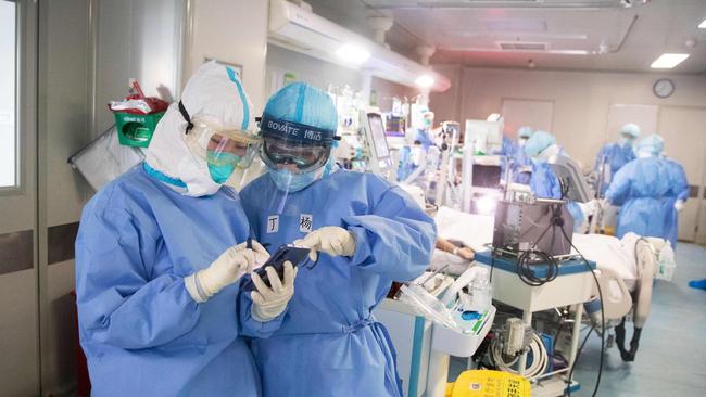 Medical staff treat check a mobile phone as they treat COVID-19 coronavirus patients at a hospital in Wuhan. Picture: AFP