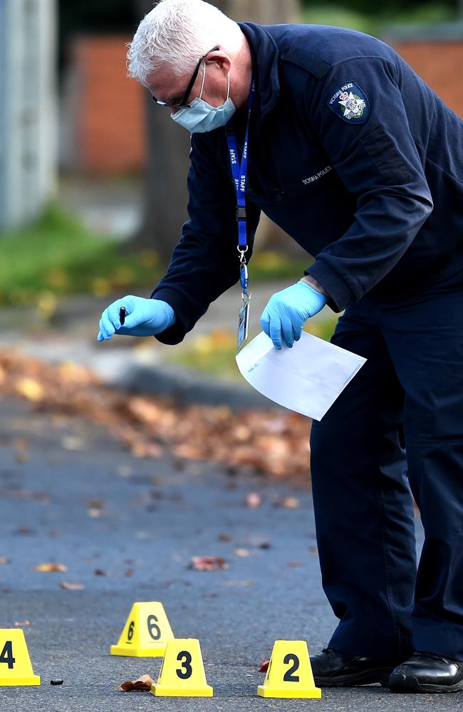 Forensic police pick up a bullet casing off the street outside the house. Picture: Nicole Garmston