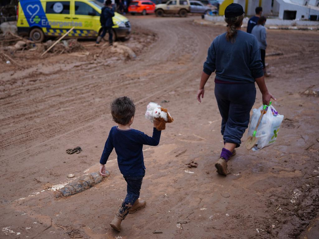 A child holds a soft toy as he walks on a muddy street in Paiporta. Picture: AFP