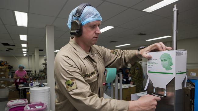 Australian Army soldier Corporal Sander Vloothuis operates the surgical face mask machine at Med-Con Pty Ltd. Picture: Defence