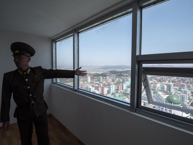 A North Korean soldier shows off the view from an apartment in the Ryomyong Street housing development following the opening ceremony. Picture: Ed Jones/AFP