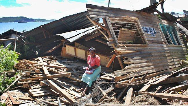 A Paga community resident sits next to her demolished home