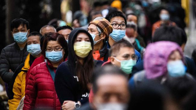 People wearing facemasks as a preventative measure following a coronavirus outbreak which began in the Chinese city of Wuhan, line up to purchase face masks from a makeshift stall after queuing for hours in Hong Kong.