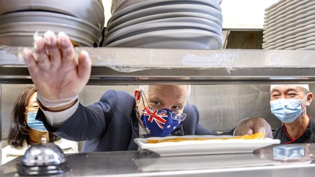 Scott Morrison rings the bell after making spring rolls at a Chinese restaurant in Box Hill, Melbourne, on Tuesday. Picture: David Geraghty