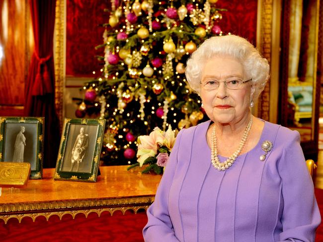 LONDON - DECEMBER 10: Britain's Queen Elizabeth II poses in the State Dining Room of Buckingham Palace after recording her Christmas Day television broadcast to the Commonwealth on December 10, 2014 in London. On the table are portraits of the Queen's grandfather King George V and Queen Mary along with a decorated brass tin given to all members of the British, Colonial and Indian Armed Forces for Christmas 1914 at the suggestion of their daughter Princess Mary. (Photo by John Stillwell - WPA Pool/Getty Images)