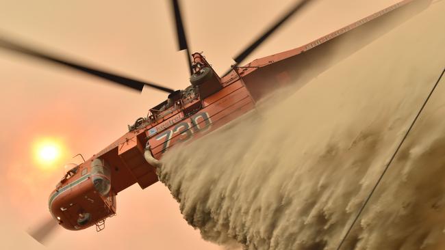 A helicopter drops fire retardent to protect a property in Balmoral, 150km southwest of Sydney. Picture: AFP