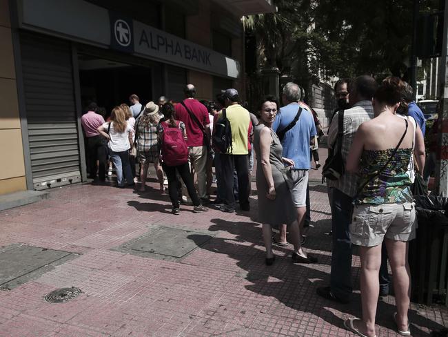 Uncertain future ... anxious Greek citizens withdraw cash at an Alpha Bank ATM in central Athens on June 28. Picture: AFP/Angelos Tzortzinis