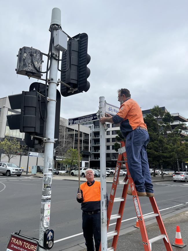 Workers put up the new street sign.