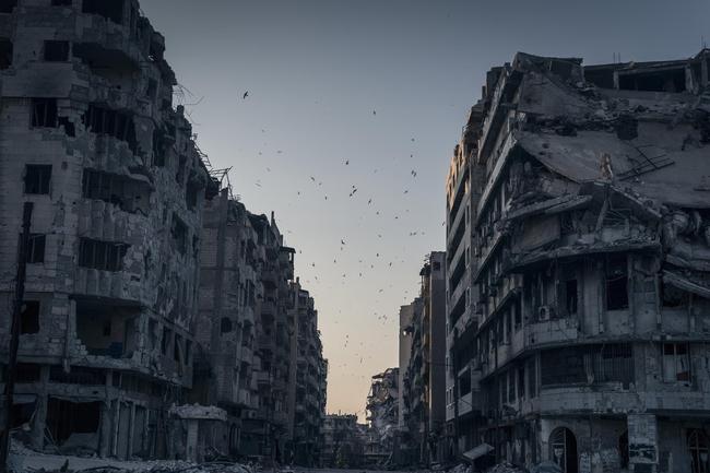 2014 National Geographic Photography Contest ... Honorable Mention Places Photo: “Destroyed Homs”. Birds fly over the destroyed houses in Khalidiya district in Homs, Syria. In the vast stillness of the destroyed city center of Homs, there are large areas where nothing moves. Then, suddenly, wind blows a ripped awning, or birds fly overhead. Location: Homs, Syria, June 15, 2014. Picture: Sergey Ponomarev for The New York Times / National Geographic 2014 Photo Contest