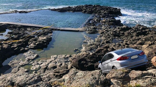 The sedan wedged between rocks above the ocean pool. Picture: FRNSW