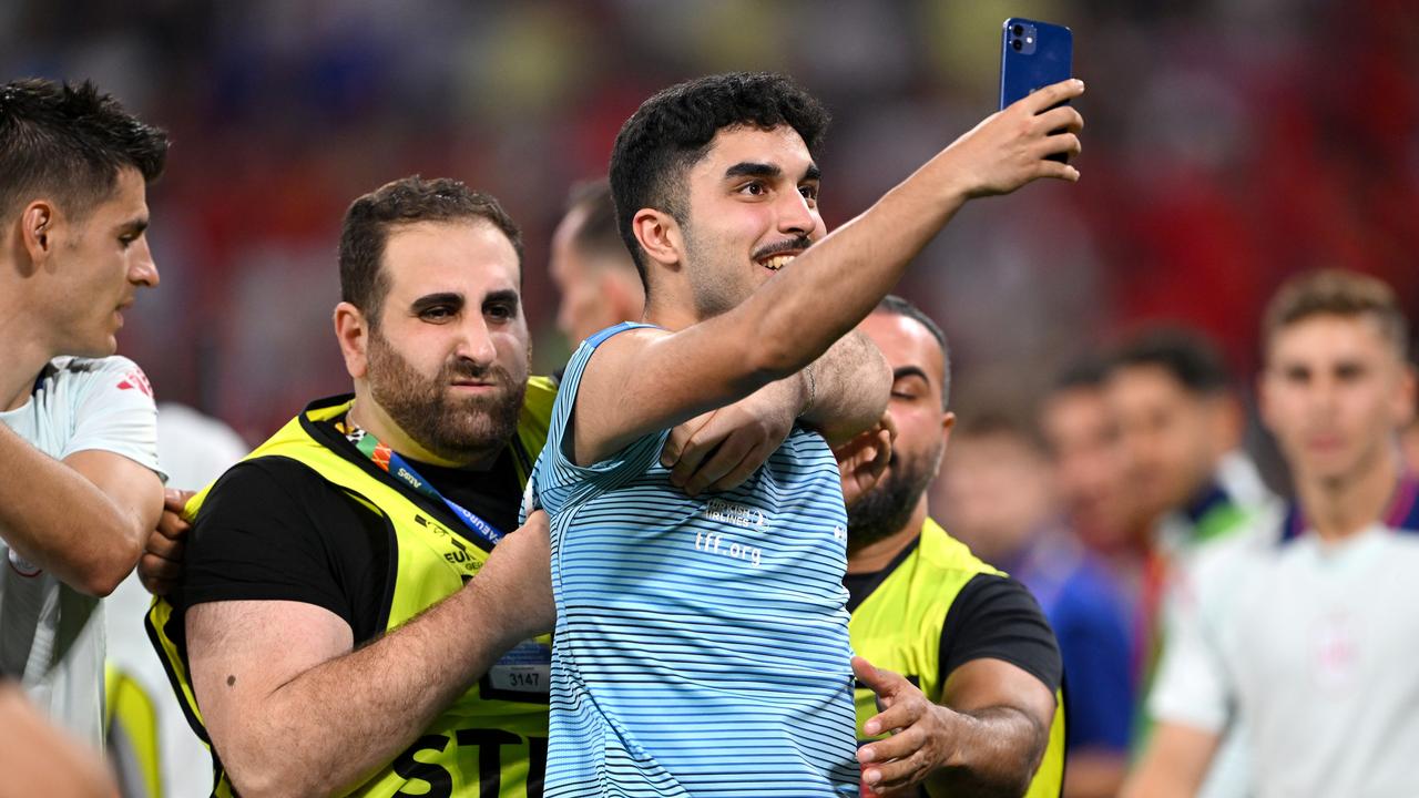 Security remove a pitch invader as he uses his mobile phone to take a selfie. (Photo by Stu Forster/Getty Images)