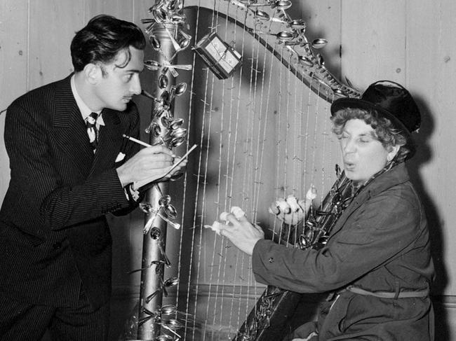 Artist Salvador Dali with comedian Harpo Marx after giving him the Christmas gift of an artwork of a harp with barbed wire strings. Circa 1936-37 Out of copyright