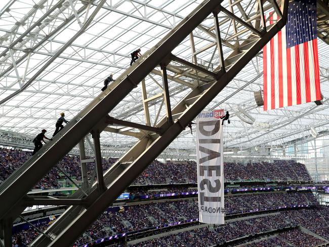 Three Minneapolis Fire Department members and one Minneapolis Police Department officer scale the rafters of US Bank Stadium where two protesters of the Dakota Access Pipeline hang.