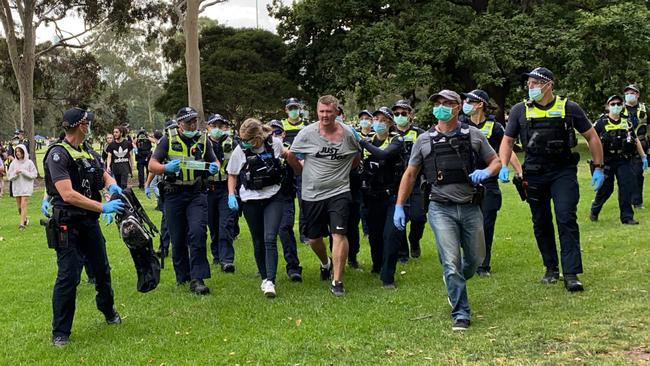 Police escort a protester from Fawkner Park. Picture: Caroline Schelle