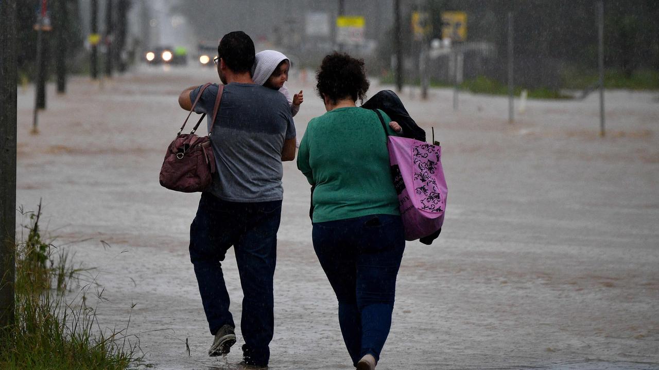 Residents wade through a flooded road during heavy rain in western Sydney on Saturday amid mass evacuations being ordered in low-lying areas. Picture: Saeed Khan/AFP