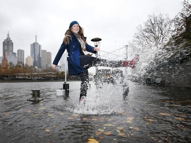 Tara Demarest makes the best of a wet situation as the Yarra River bursts its banks in Melbourne. Picture: David Caird