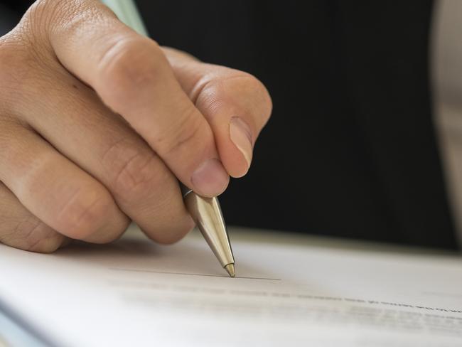 CAREERS: Low angle view of a woman signing contract with a pen.