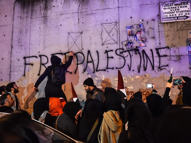 A protester spray-paints "Free Palaestine" on a wall during a demonstration against the US and Israel in front of the US consulate in Istanbul. Picture: AFP/Ozan Kose