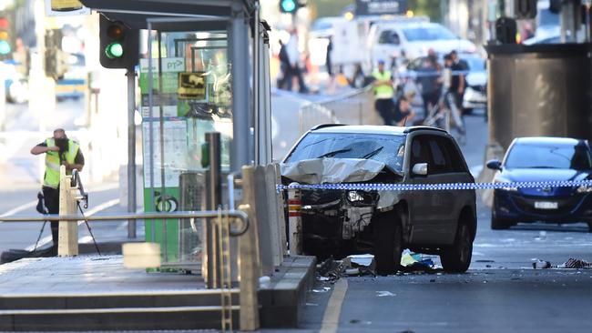 A white SUV sits in the middle of the road as police and emergency personnel work at the scene of where a car ran over pedestrians in Flinders Street in Melbourne. Picture: Mal Fairclough
