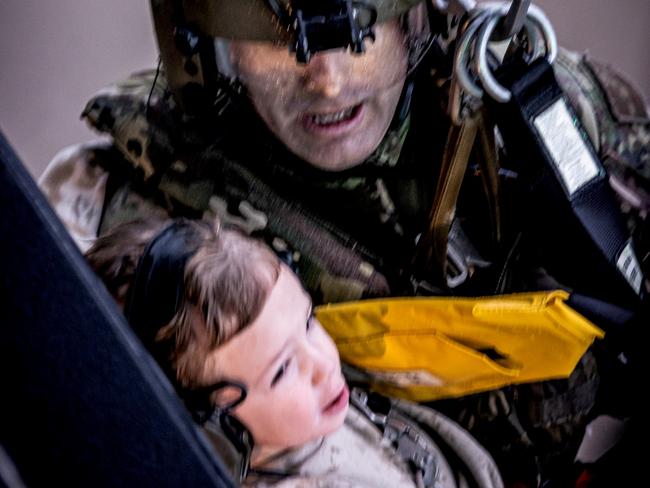 An Australian Army aircrewman from the School of Army Aviation and a young child are winched aboard an MRH-90 Taipan helicopter near Lismore, New South Wales during Operation Flood Assist 2022.