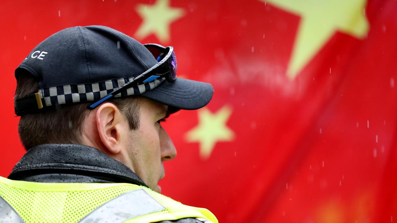 A police officer stands in front of a Chinese flag during a pro-democracy Hong Kong rally in Adelaide. Picture: AAP Image/Kelly Barnes