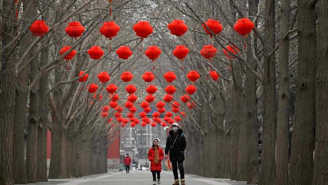 A woman and a child walk along a Beijing road with red lanterns hanging on trees for the upcoming Chinese Lunar New Year celebrations. Picture: Wang Zhao/AFP